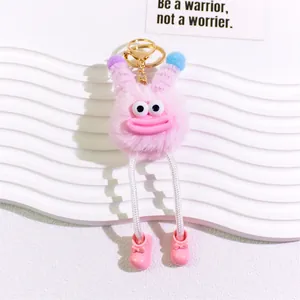 Close-up of pink plush monster keychain with big eyes and sausage lips on white stand