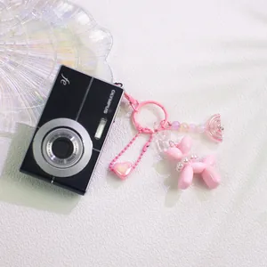 Pink balloon dog keychain with pearl collar and heart charm on a stylish white background