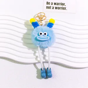 Close-up of a blue plush monster keychain with big eyes and star-shaped golden clasp
