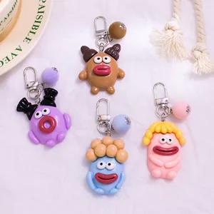 Vue à plat de quatre porte-clés rigolos à bouche de saucisse avec boules en peluche