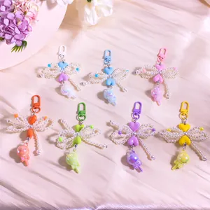 Flat lay of beaded bow keychains with colorful hearts and glittery lollipops on silk