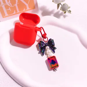 Vue détaillée de l'étui en silicone rouge avec nœud irisé et breloque en perles sur plateau