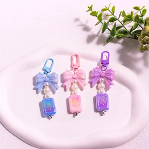 Détail de porte-clés nœud en résine pastel avec perles et breloques de cartes de jeu
