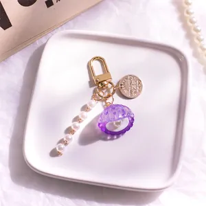 Dettaglio di un portachiavi a conchiglia viola con perle bianche e moschettone dorato