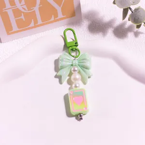 Détail du porte-clés à nœud vert avec perles blanches et breloque carte à jouer coeur