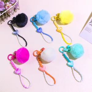 Detailed view of colorful plush pompom keychains with heart pendants and beaded chains