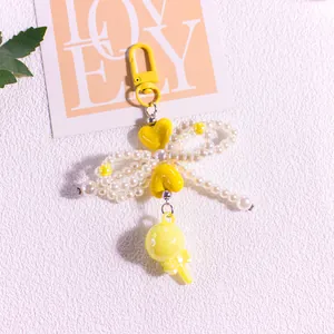 Detail of beaded pearl bow keychain with yellow hearts and a lollipop pendant charm