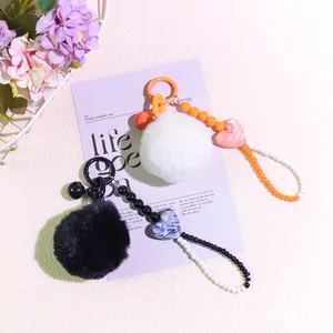 Detail of plush pom pom keychain with colorful beads and marble heart charm decoration