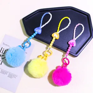 Close-up of colorful DIY pompom charms with marble hearts and beaded chains for bags