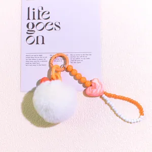 Detail of sweet DIY plush ball pendant with orange beads and pink heart charm