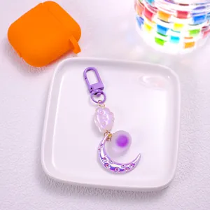 Close-up of purple moon and cloud keychain accessories on a white ceramic tray