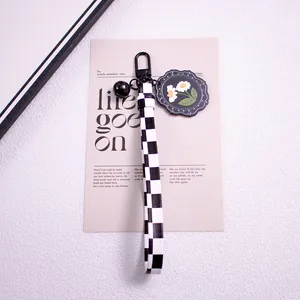 Close-up of checkerboard ribbon keychain with daisy pendant and black metal clasp
