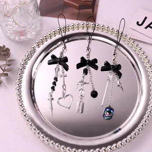 Macro shot of three Y2K gothic style phone charms with black bows and metal crosses
