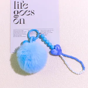 Detail of sky blue fluffy faux fur pompom keychain with beaded chain and heart charm