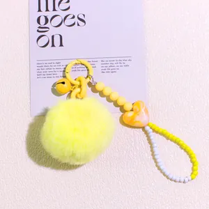 Close-up of fluffy yellow pompom keychain with beaded strap and marble heart bead