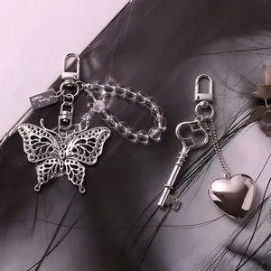 Detail van vlinder en hart metalen bedeltjes met kralen op zwarte veren decor