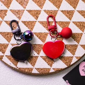Polished metallic heart keychains in purple and red on a cork board background