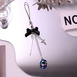 Detail of Y2K black bow keychain with silver chain and purple iridescent metallic ball