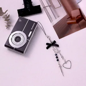 Macro detail of Y2K gothic bow, cross, and syringe charms on a vintage camera strap