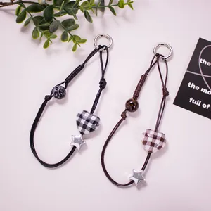 Detailed view of woven phone charms featuring checkered hearts and silver star pendants