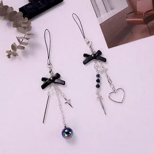 Detail of Y2K gothic phone charm with black bow, metal cross, and syringe pendants