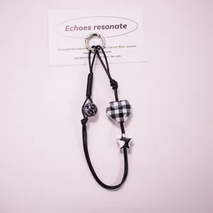 Macro shot of phone lanyard detail with checkered heart bead and silver star charm