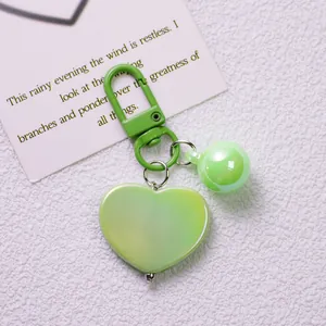 Detail of fresh green heart-shaped keychain with gradient pearlescent finish and mini charm