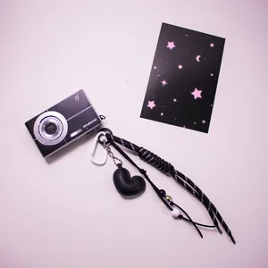 Porte-clés cœur tressé avec pendentif en cuir noir et perles sur fond d'appareil photo