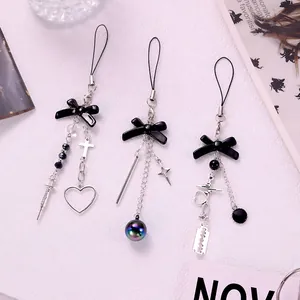 Close-up of Y2K gothic phone charms with black bows and silver syringe pendants