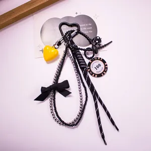 Macro view of a stylish bag charm featuring a yellow heart, poker chip, and woven cord