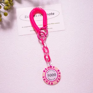 Macro detail of bright pink coil bracelet keychain with Monte Carlo Poker chip charm