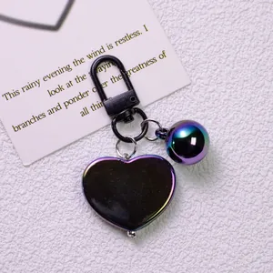 Detailed macro view of iridescent heart-shaped keychain with matching bell and black hardware