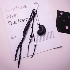 Gros plan du pendentif cœur en cuir noir avec corde tissée et perles sur magazine