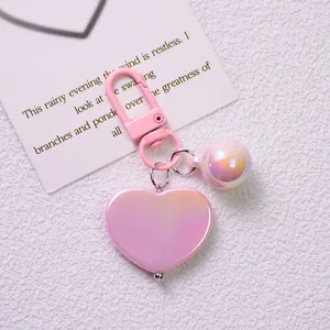 Close-up of heart-shaped gradient keychain with iridescent pearl on a poetic card
