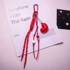 Détail d'un pendentif coeur en cuir rouge avec corde tressée et perles sur magazine