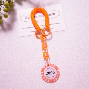 Macro shot of orange coil keychain with retro pink poker chip pendant and plastic chain