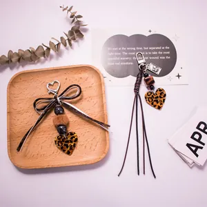 Detail of leopard print heart keychain with faux fur ball and retro bow accessory