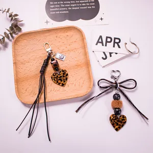 Leopard print heart keychain with fur ball tassel and bow charms on white surface
