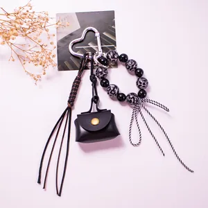 Close-up of heart clasp with black leather mini pouch and leopard print beaded keychain