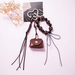 Detail of leather mini pouch keychain with leopard beads, heart clasp, and woven tassel