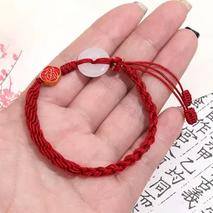 Detailansicht eines roten geflochtenen Armbands mit weißem Jadestein und Fu-Anhänger