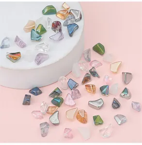 Nahaufnahme unregelmäßiger bunter Glasperlen für DIY-Schmuck auf rosa Hintergrund