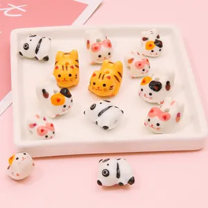 Hand-painted ceramic cat and panda beads for DIY jewelry making on a pink background