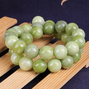 Macro shot of natural green jadeite beads with smooth oily finish on wooden stand