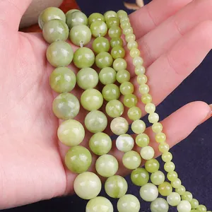 Close-up of four sizes of polished light green jade beads held in hand for DIY jewelry