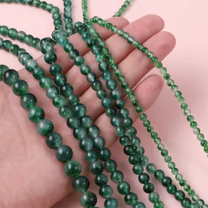 Natural green chalcedony round beads in various sizes held for size comparison