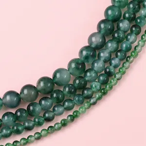 Natural dark green jade beads in four various sizes on a soft pink background