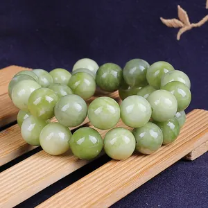 Natural light green jade round bead bracelet on bamboo mat with deep blue background