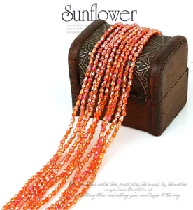 Detail of warm orange faceted crystal glass beads for DIY jewelry making displayed on a wooden box