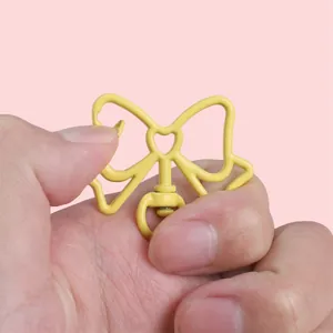 Porte-clés nœud papillon jaune en alliage avec détail cœur sur fond rose doux